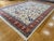 This large handmade Tabriz-style rug features a detailed floral allover pattern with a soft ivory field, deep red border,...