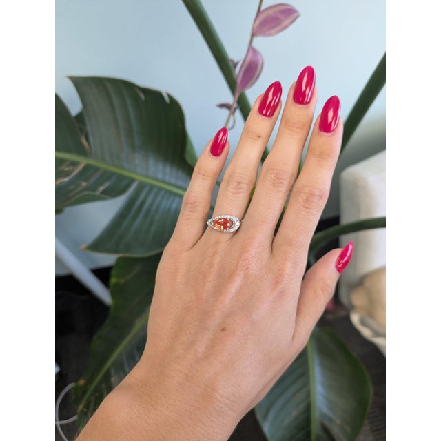 A 1.76-carat padparadscha sapphire glows in its signature pink-orange, set east-west at the centre of this solid 14K white...