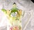 This is an unmarked chocolate pot in white and green with pink and yellow flowers on the front, peach and purple...