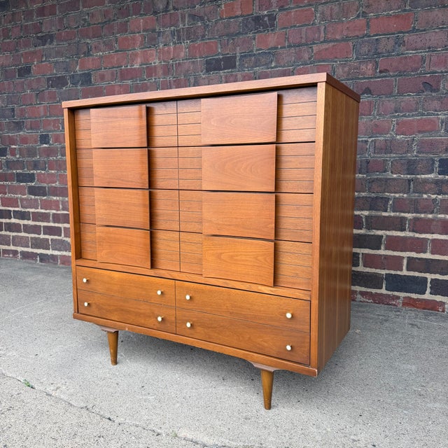 A distinctive mid-century modern walnut highboy dresser by Johnson Carper, dating to approximately the 1960s. The dresser...