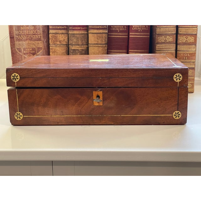 An elegant 19th-century English portable writing slope or lap desk in richly figured mahogany, ornamented with brass...