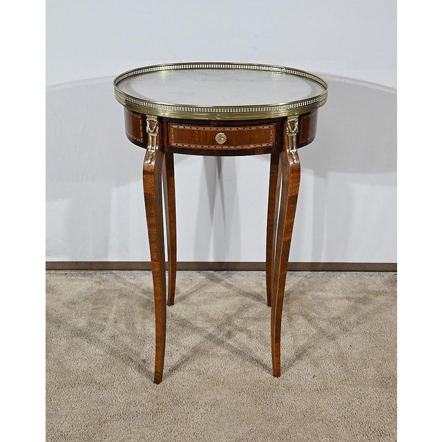 Charming mahogany living room table and mahogany veneer, oval shape and having a belt drawer. The facade is encrusted with...