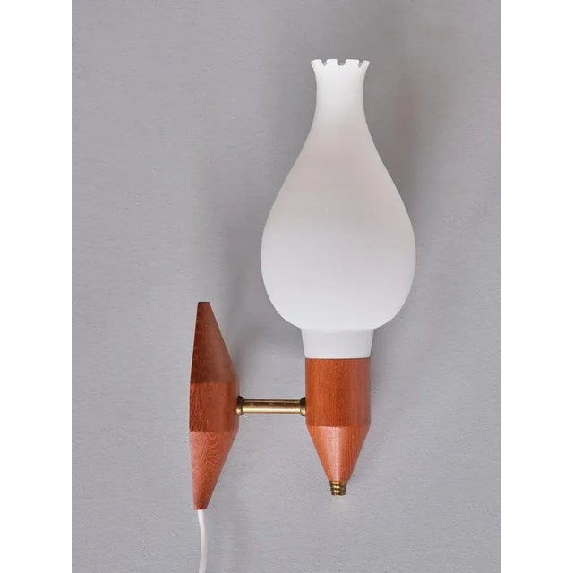 This elegant pair of wall lights was produced in Sweden in the 1950s. The design consists of a holder and back plate in...