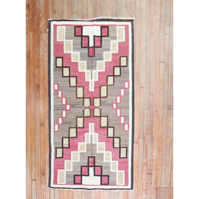 A highly decorative 20th-century American Navajo rug with a geometric tribal design with pink, cream ,camel and brown...
