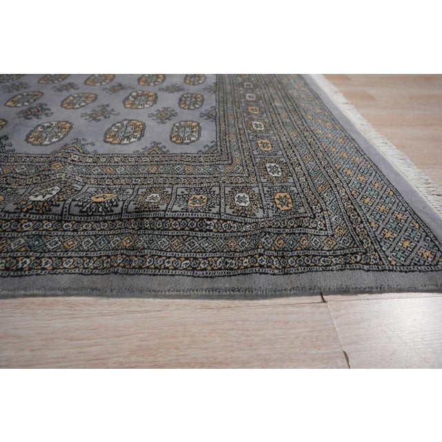 A hand-knotted wool rug, made in India and measuring 4' x 6'. Floral drawing carried across the field inside a traditional...