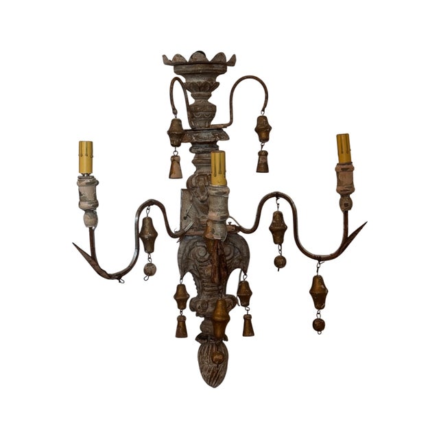 A pair of wall sconces with scrolling arms and multiple candle sockets, each decorated with small hanging bell elements...