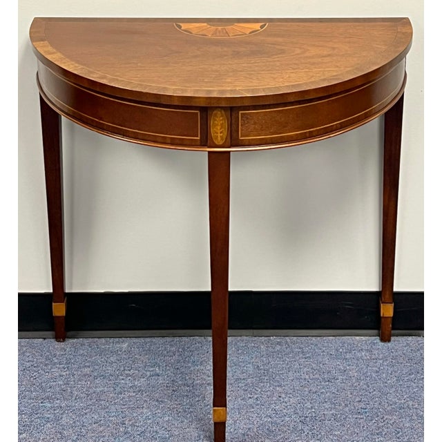 Baker Furniture American Federal-style inlaid mahogany demilune console table offers a masterful blend of classical...