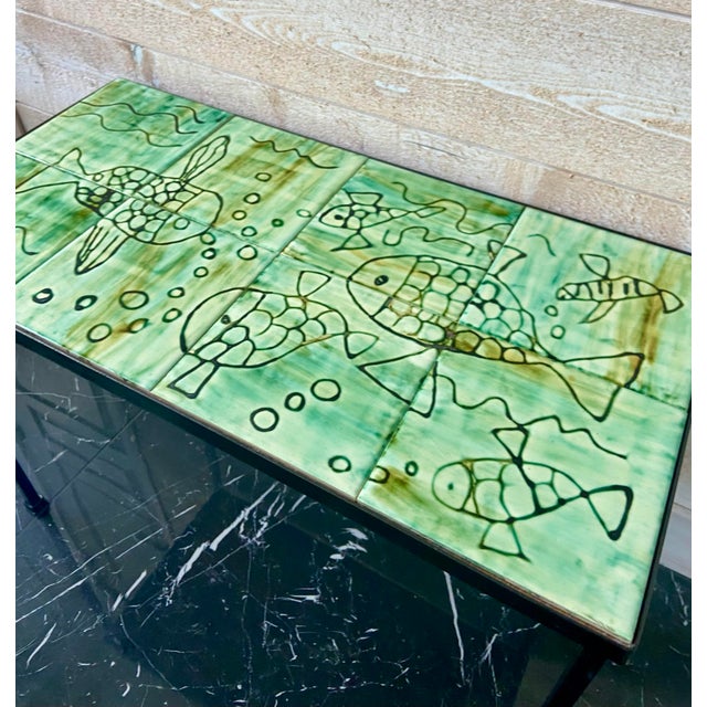 Elegant mid-century coffee table featuring a ceramic tile top composed of hand-decorated glazed tiles forming a continuous...