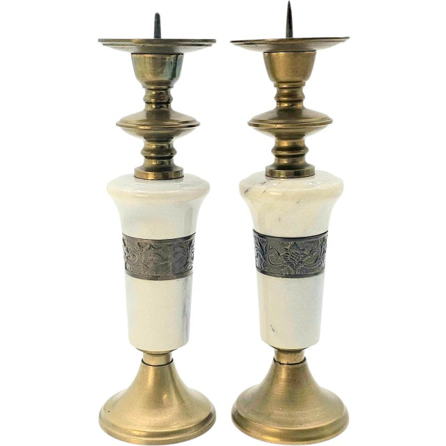 Graceful silhouettes rise in brass and marble, their white stone bodies encircled by a dark floral band, hand-etched with...