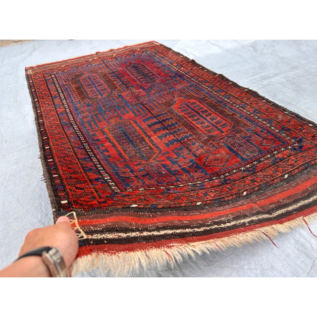 This antique hand-knotted Baluch rug features the classic Kalamdani "pen-case" design — four tall paneled devices filled...