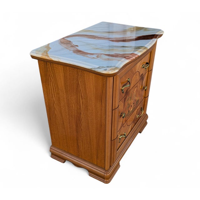 Italian provincial style nightstand with a faux marble top, decorative marquetry-style front panel, and brass-tone...