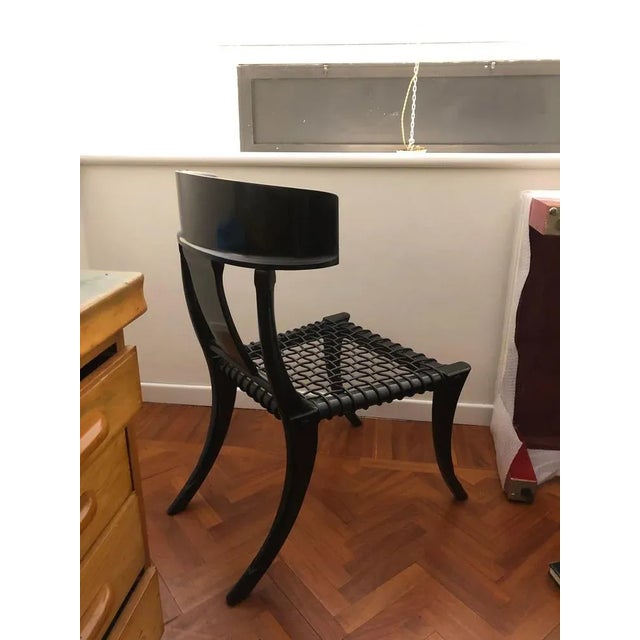 Klismos dining chairs with saber legs, black lacquered wood and black woven leather seats. Italian artisanal production by...