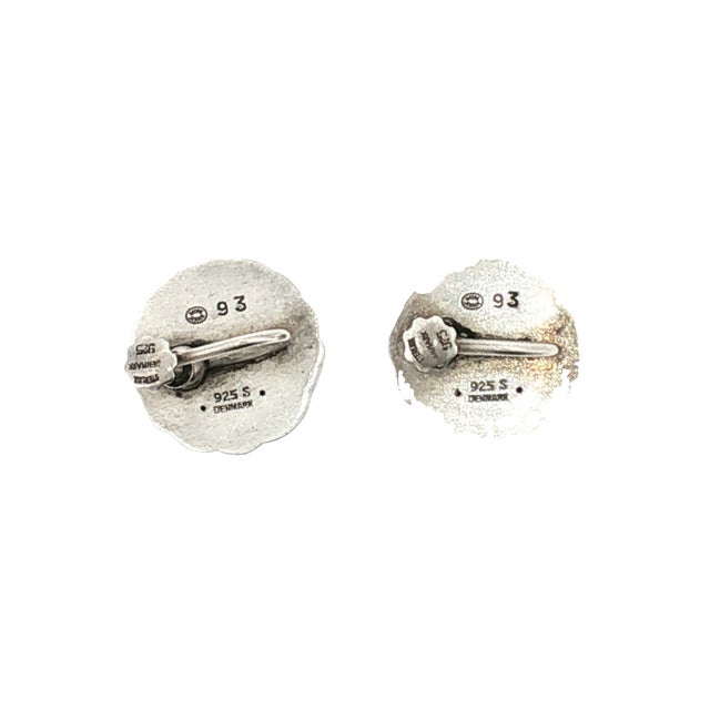 A pair of mid-20th-century sterling silver earrings by Georg Jensen, Tulip design #93. These feature an intricate swirling...