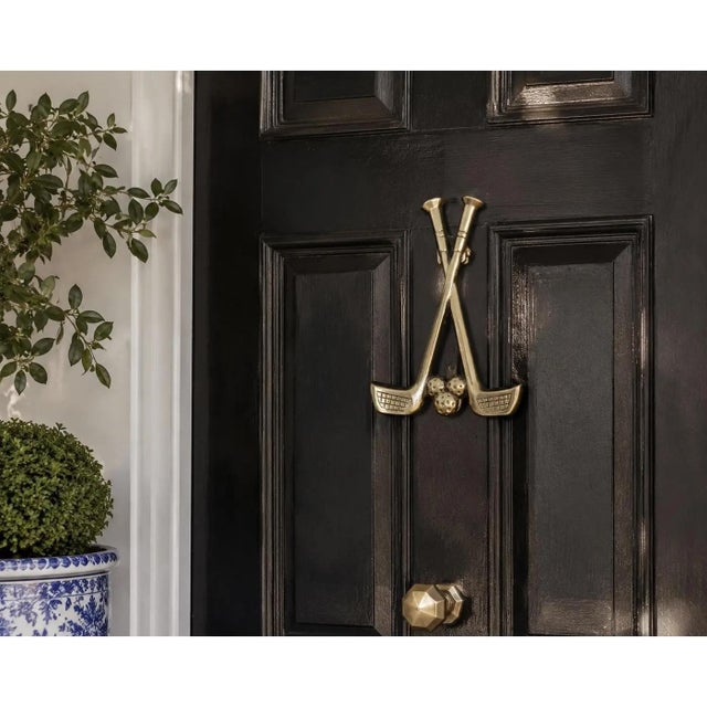 A distinctive vintage door knocker cast in brass as a pair of crossed golf clubs, complete with three textured golf balls...