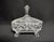 A striking lidded cut crystal candy dish with feet. The rectangular dish features four curved feet, a tall steeple finial,...