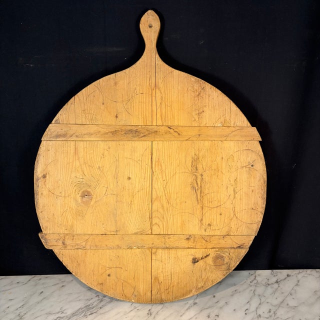 Vintage French round bread board or dough board, handcrafted from solid hardwood pine with a shaped handle and a warm,...
