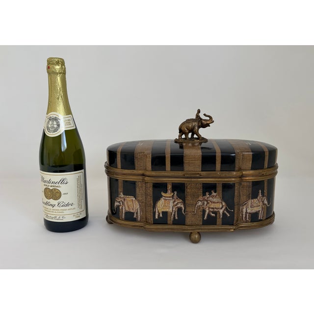 Impressive vintage decorative keepsake box by Castilian Imports, featuring an exotic elephant-procession design in black,...