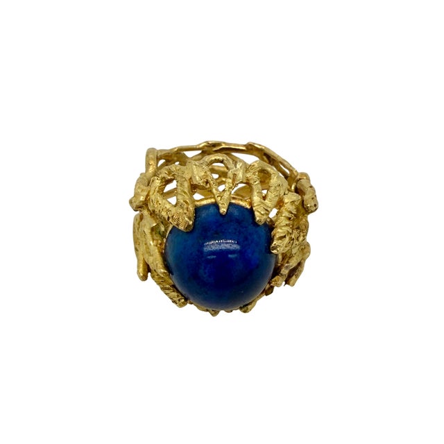 A striking mid‑century 18K gold ring featuring a domed cabochon lapis set in an openwork sculptural gold mounting. The...