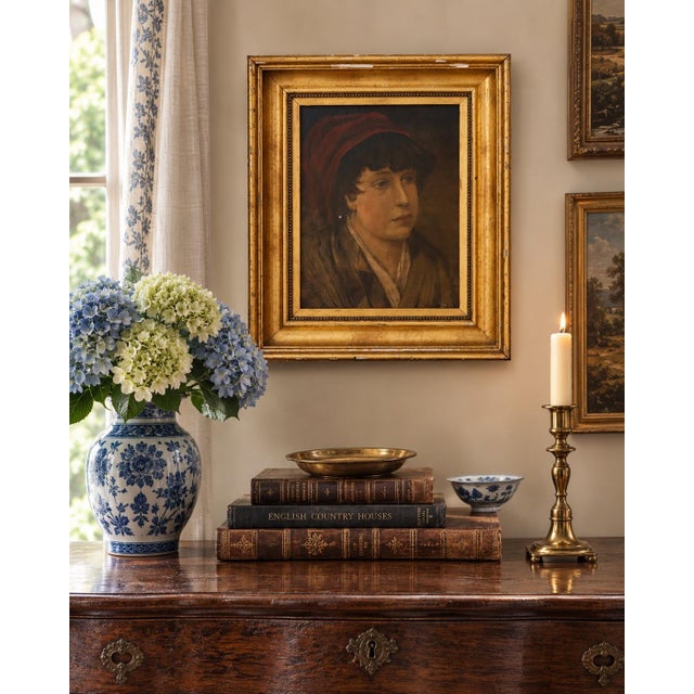 A quietly compelling early 20th century oil on canvas portrait depicting a young boy in a red cap, signed Mary E. Southard...