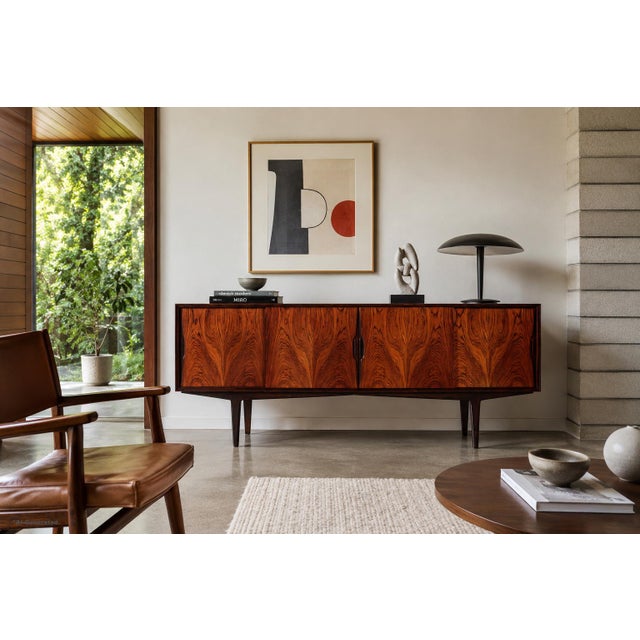Dating to the 1960s, this Danish modern Brazilian rosewood credenza by Knud Nielsen for Losning Mobelfabrik showcases the...