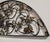 A substantial demilune (half-round) wall grille in the Rococo Revival style, featuring scrolling acanthus leaves, floral...