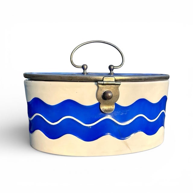 A vintage porcelain and enamel lidded container features a striking, high-contrast wave motif in cobalt blue and crisp...
