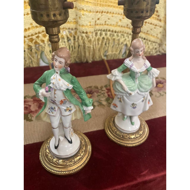 This charming pair of vintage porcelain figurine lamps features a Rococo-style couple dressed in elegant 18th-century...