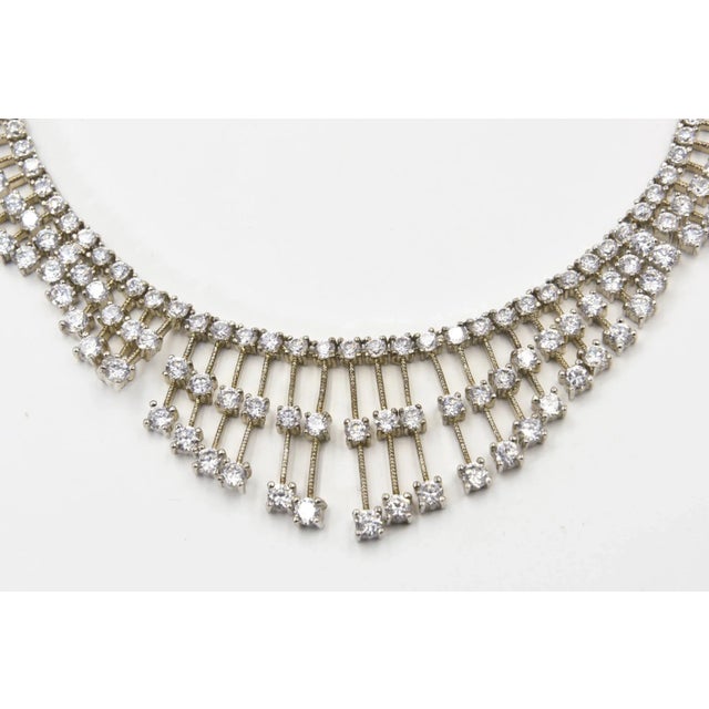 Red carpet style tassel bib necklace made up of various length lines that each have three prong set clear crystals. The...