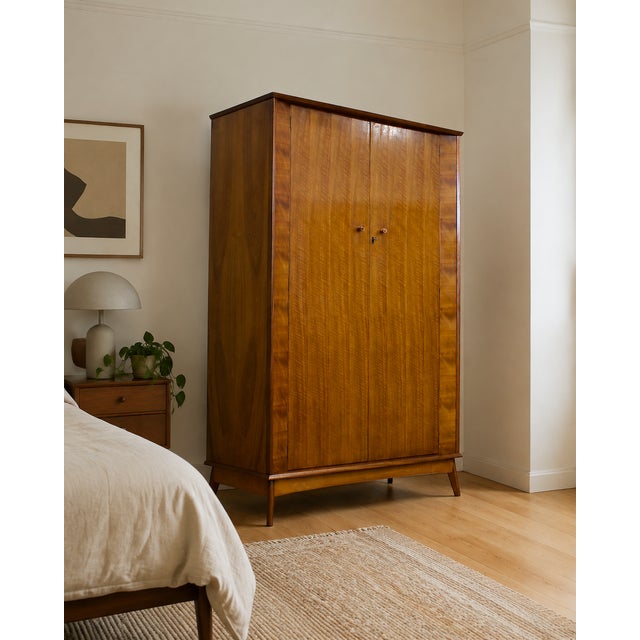 A stylish mid-century walnut wardrobe by Alfred Cox, featuring beautifully figured ripple walnut veneers, tapered legs and...