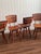 This set of four mid-century modern dining chairs features classic slatted backs and warm-toned wood with a natural, even...