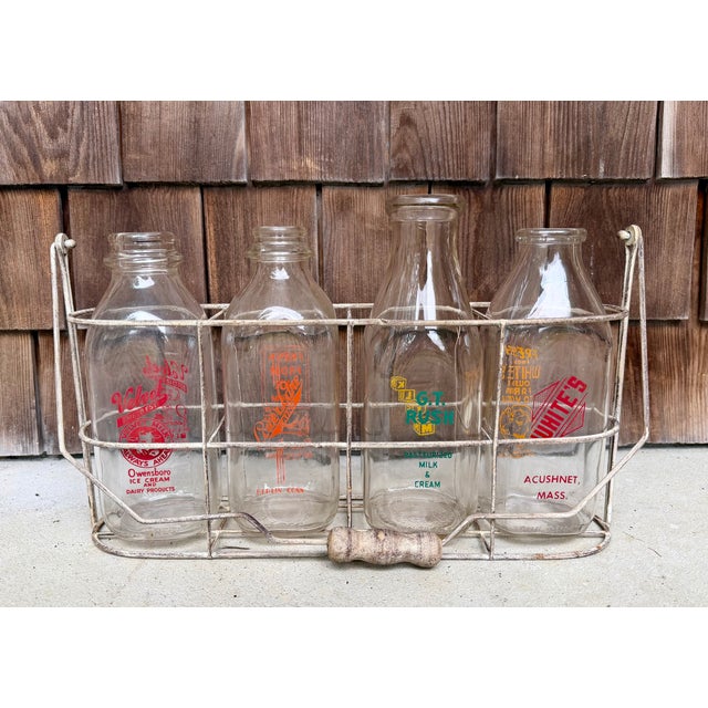 Four vintage quart milk bottles in a wood-handled wire carrier--perfect to display flowers and add character to your...