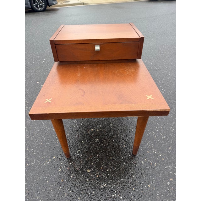 Mid century nightstand by Merton Gershun for Martinsville furniture. The nightstand features a two tier top with a drawer...
