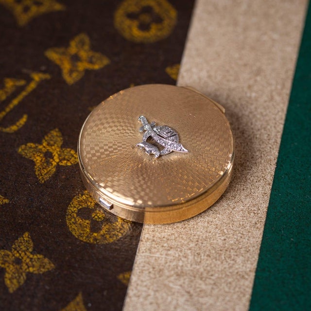 A 20th century art deco french 18k gold and diamond compact. Circular in form with an all-over engine-turned decoration....