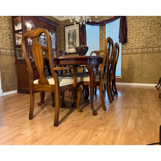 Elegant cherry dining table with six coordinating chairs, two extension leaves, and custom protective table pads. The set...