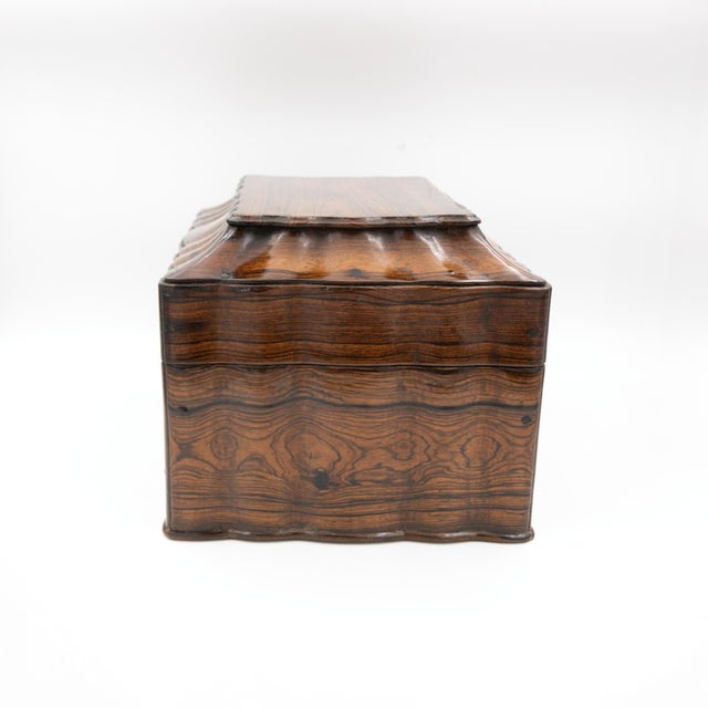 A serpentine-lidded coromandel box with a moulded top and continuous undulating sides. The exterior displays...
