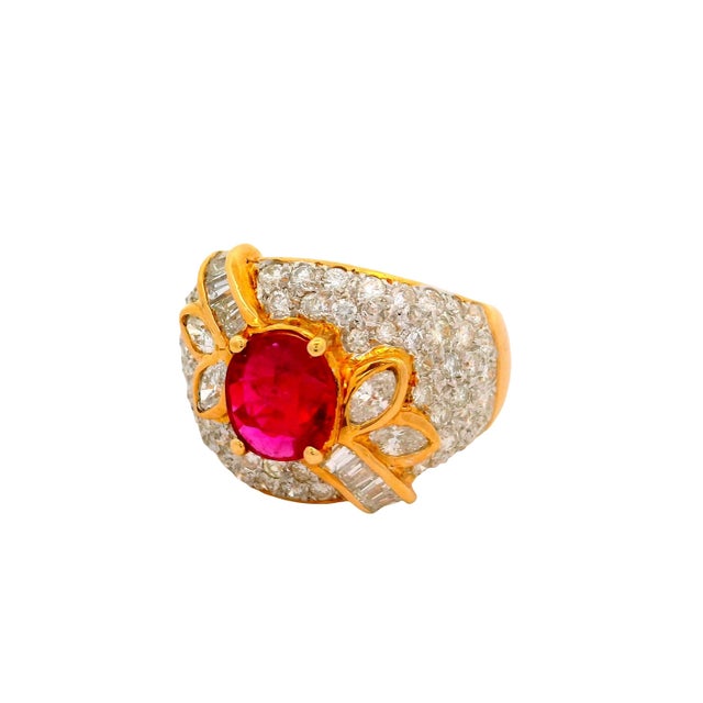 A striking ring featuring a vivid red oval ruby weighing 1.39 carats, set prominently at the center. Surrounding the ruby...