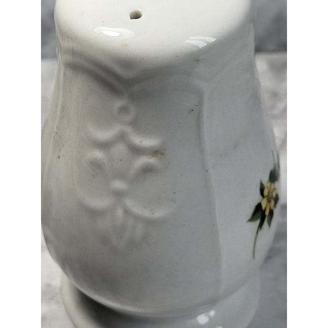 Lovely salt & pepper shakers each have their stoppers. White porceelain with a bulbouse shape and floral accent. Will go...