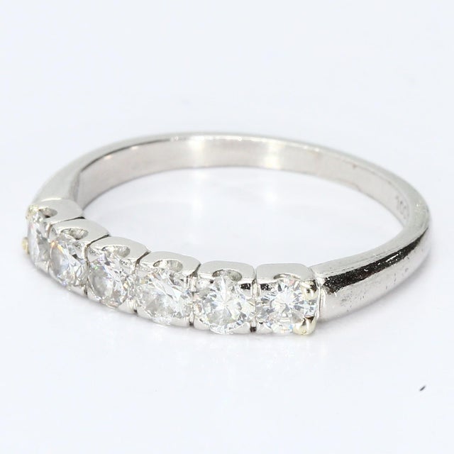 This elegant platinum band ring showcases a refined design with a row of sparkling diamonds. The round white diamonds,...