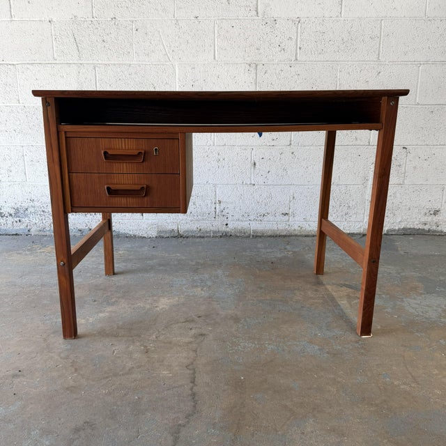 A compact Danish modern teak writing desk dating to the 1960s. The desk has a clean, practical form, with a rectangular...