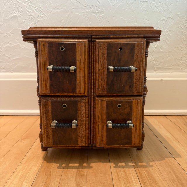 A charming early 20th‑century oak sewing cabinet featuring four deep drawers, decorative applied burled wood faces, and...