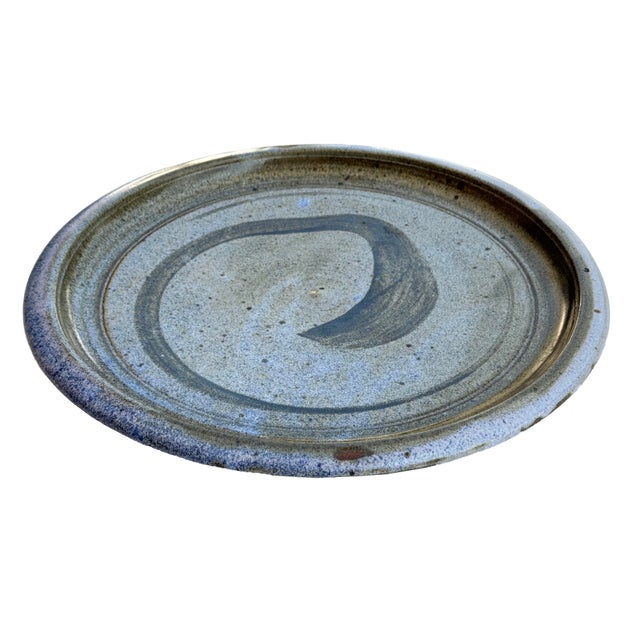 A modernist mid-century stoneware charger. The top has a simple abstract design. On the bottom there is a nice ring design...