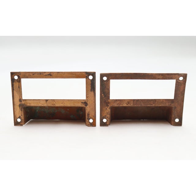 Vintage brass drawer bin pulls with a copper-bronze finish and label slots. The original mounting screws are not...