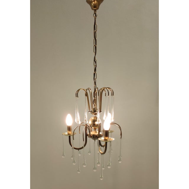 Made in Italy, 1970s. This chandelier features a brass frame with three arms and 28 Murano glass drops. It is vintage,...