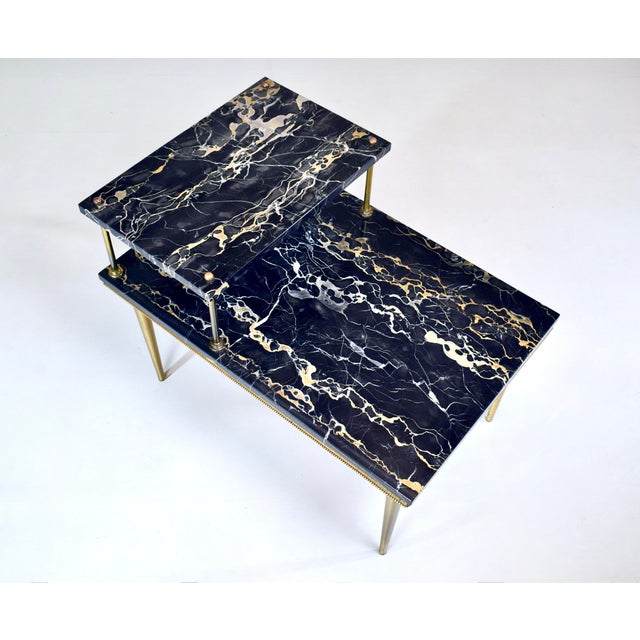 An Italian Portoro Marble two step side table embellished with striking jewel like brass accents, brass joinery and...