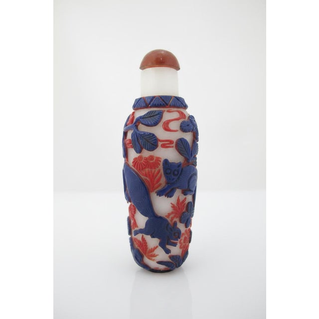 Chinese multicolor overlay glass snuff bottle most likely from the Qing dynasty era. Featuring intricately carved blue and...