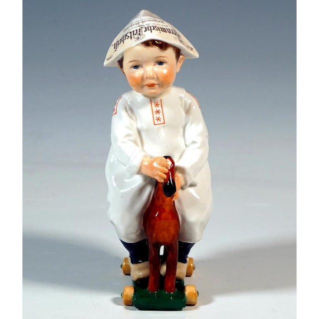 Boy in a long white shirt with a newspaper cap riding on a wooden horse with wheels. Modeling and painting of the finest...