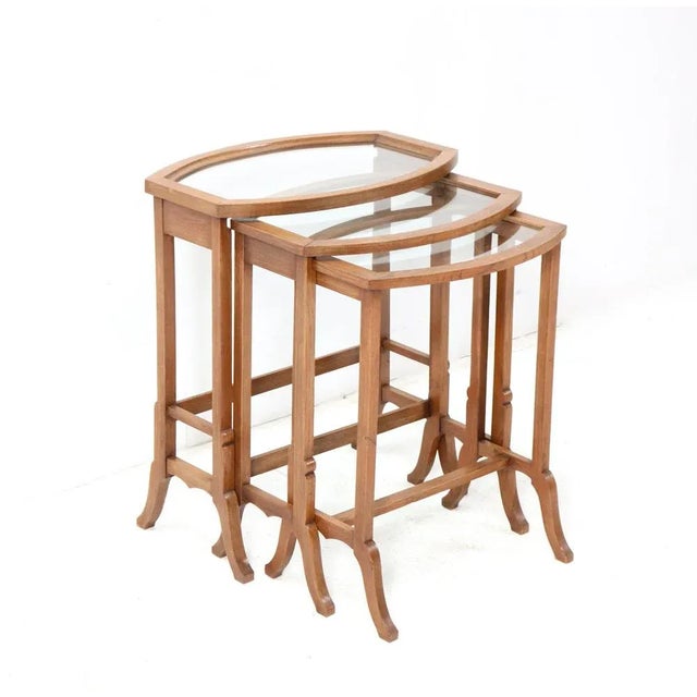 Stunning and rare set of three Art Nouveau nesting tables. Solid oak and elegant shaped frames with glass tops. This...