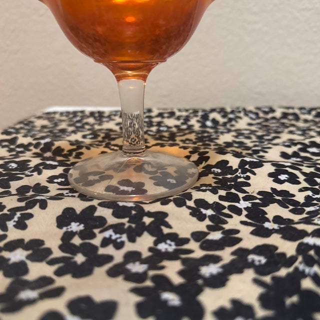 This elegant footed compote (or candy dish) features a classic marigold carnival glass finish with a vibrant iridescent...