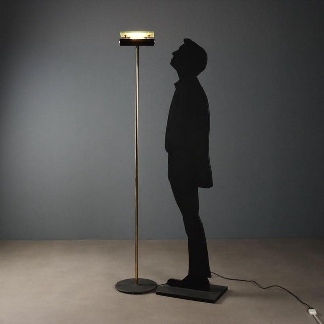 1980s Italian-made floor lamp. The structure consists of a cast iron base and a brass stem, adding a touch of elegance and...