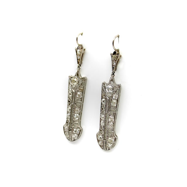 These elongated 18k white gold filigree earrings have an exquisite design that is lace-like with floral openings and zig...